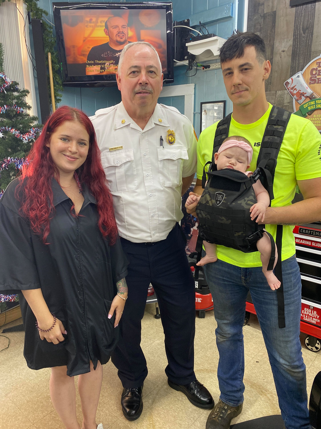 Josette Manzolillo (left), daughter of the owners of Jenny’s JNT Beauty Barbershop, with partner Matt Stevenson (right), baby Scarlett (front) and deputy inspector Bill Read (right) of the 7th Precinct.